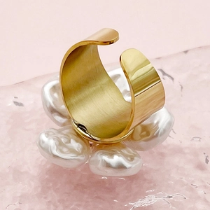 Macro shot of gold-plated floral ring with baroque pearls and brushed metal texture