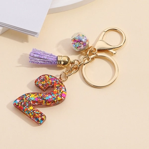 Detailed close-up of resin number 2 keychain with sequins, purple tassel and golden clasp