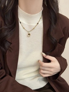 Gros plan du collier vintage en œil de tigre sur mannequin en blazer marron chic
