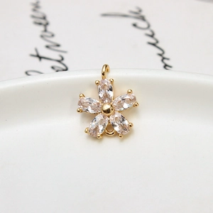 Macro detail of a 5-petal flower charm featuring clear zircons and gold-plated copper