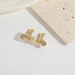 Macro shot of C-shaped safety pin earrings with purple pavé crystals on a stone base