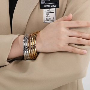 Stacked metallic bangles in gold, silver, and bronze with engraved heart patterns