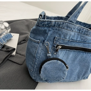 Detailed close-up of blue denim tote bag with round coin purse and exterior zipper pockets