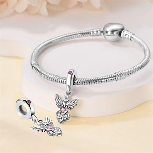 Detail of silver angel wing charm with pink heart gemstone on a beaded bracelet
