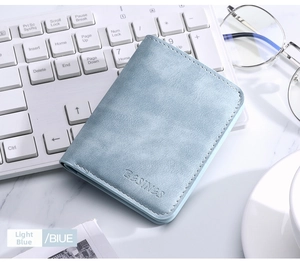 Close-up of light blue slim card holder with fine leather texture and embossed logo