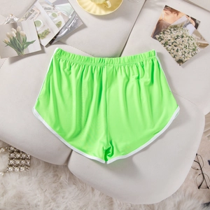 Close-up of fluorescent green elastic yoga shorts with white piping on a textured sofa