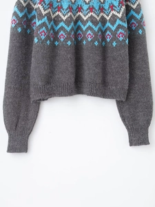 Detailed view of grey knit sweater with Fair Isle patterns and ribbed cuffs and hemline