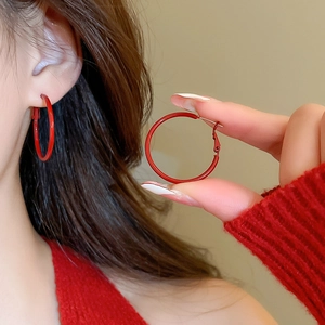 Detailed close-up of vibrant red hoop earrings with glossy finish on a female model