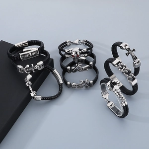 Detail of men's black braided leather bracelets with silver skull and anchor charms