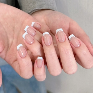 Close-up of French tip press-on nails in nude pink gradient and coffin shape