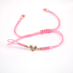Macro shot of pink braided rope bracelet with a gold heart charm and pink zircon stones