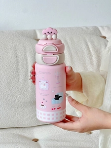 Détail du thermos rose avec couvercle nuage 3D tenu à la main sur fond de tissu
