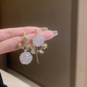 Detailed close-up of asymmetric gold rose earrings with pearlescent lavender petals