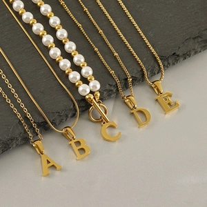 Gold stainless steel initial necklaces featuring letters A to E and a pearl detail strand