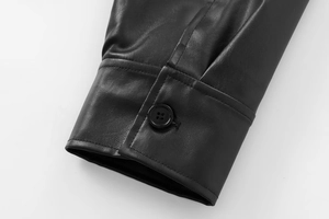 Detailed close-up of a black faux leather bomber jacket sleeve with a round button