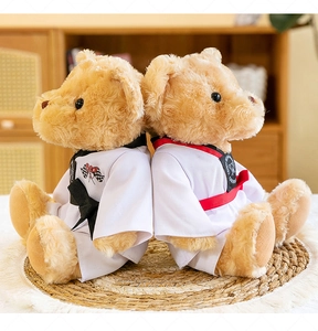 Paire de nounours mignons en tenue de taekwondo assis dos à dos sur un tapis.