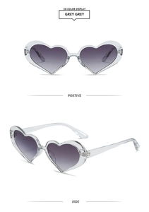 Detail view of transparent grey heart-shaped sunglasses with gradient lenses