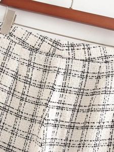 Close-up of the black and white plaid tweed texture and waist detail of the elegant set