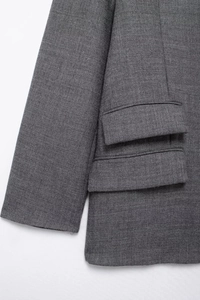 Detailed macro view of the grey wool blend blazer featuring double-flap pockets and texture