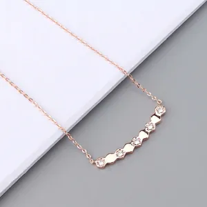 Close-up of rose gold hexagonal pendant set with sparkling zircon on a delicate cross chain