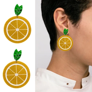 Detailed view of orange slice acrylic earrings with glitter yellow finish and green leaves