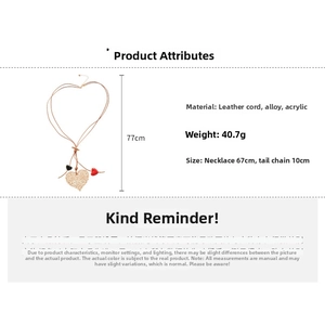 Three heart pendants in red, black, and gold on a brown leather cord necklace
