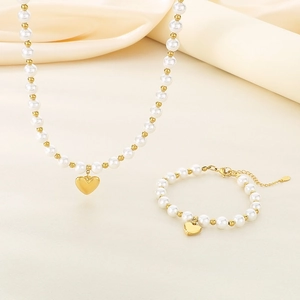 Detailed view of beaded pearl necklace and bracelet set with golden heart charms