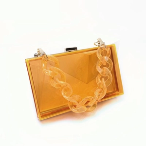 Detail view of transparent amber acrylic evening bag with matching chunky resin chain handle