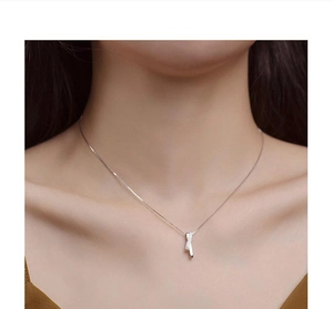 Close-up of a silver geometric pendant necklace with zircon worn on a model's neck