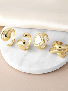 Close-up of four gold heart rings with cubic zirconia on marble and silk fabric