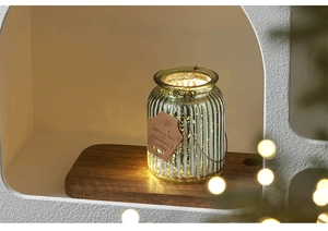 Close-up of glass Christmas tree jar with warm LED light and vertical stripe texture