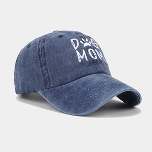 Close-up of white Dog Mom embroidery and paw print on washed navy denim baseball cap