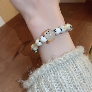 Detailed view of handmade beaded bracelet with cute dog and bone charms on wrist