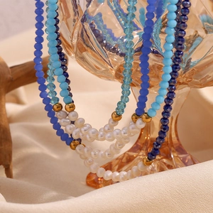 Detail of blue faceted crystal beads and white freshwater pearls on a gold necklace
