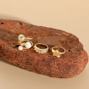 Detailed view of three-piece gold plated ring set with pearl and star on bark