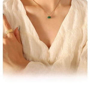 Detail of 18k gold plated titanium necklace with emerald zircon and matching wide ring