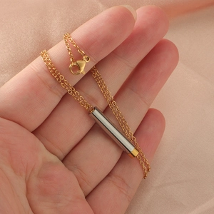 Minimalist gold chain necklace with a two-tone silver and gold cylinder pendant