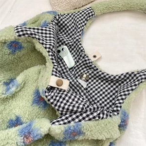 Detail view of plush tote bag with magnetic closure and checkered lining interior