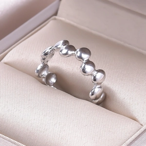 Close-up of polished silver bubble ring with wavy bead design in a satin jewelry box