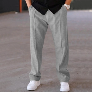 Detail view of men's grey knitted cotton sweatpants with waist drawstring and front seams