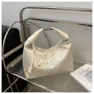 Close-up of cream satin handbag with floral embroidery and pearl bead charms