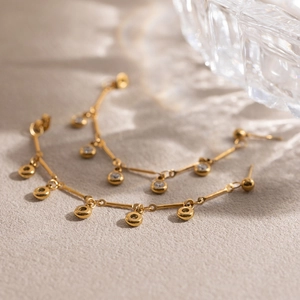 Close-up of gold tassel earrings with zircon circles on a soft textured background