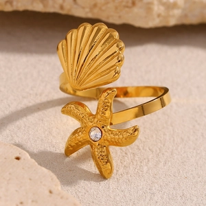 Macro detail of 18K gold plated starfish and shell ring with sparkling zircon stone