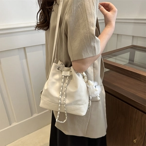 Fashionable cream drawstring bucket bag with chain strap and cute plush charm detail