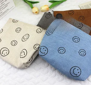 Detailed top view of corduroy makeup bags with smiley faces on heart quilted background