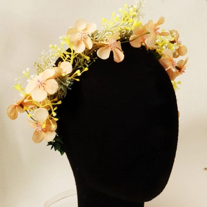Close-up of artificial floral headband with orange flowers and green leaves on a model