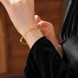 Dettaglio del bracciale a quadrifoglio in oro 18k con zirconi bianchi al polso donna