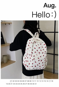 Detail of white corduroy backpack with red strawberry print on female model