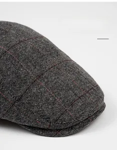 Macro view of dark grey herringbone tweed with red checkered lines on a wide cap brim
