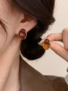 Detailed close-up of 18K gold plated irregular amber resin stud earrings on model
